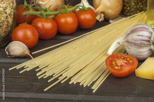 Preparing homemade pasta. Pasta and vegetables on a wooden table. Dietary food. Pasta, tomatoes, onion, olive oil and basil on wooden background. 
 photo