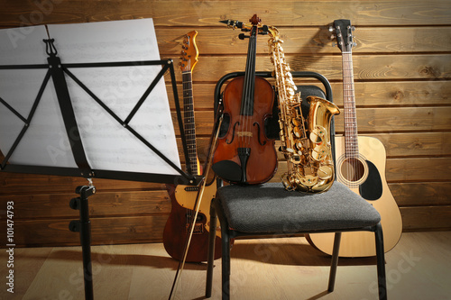 Musical instruments on a chair and note holder against wooden background photo
