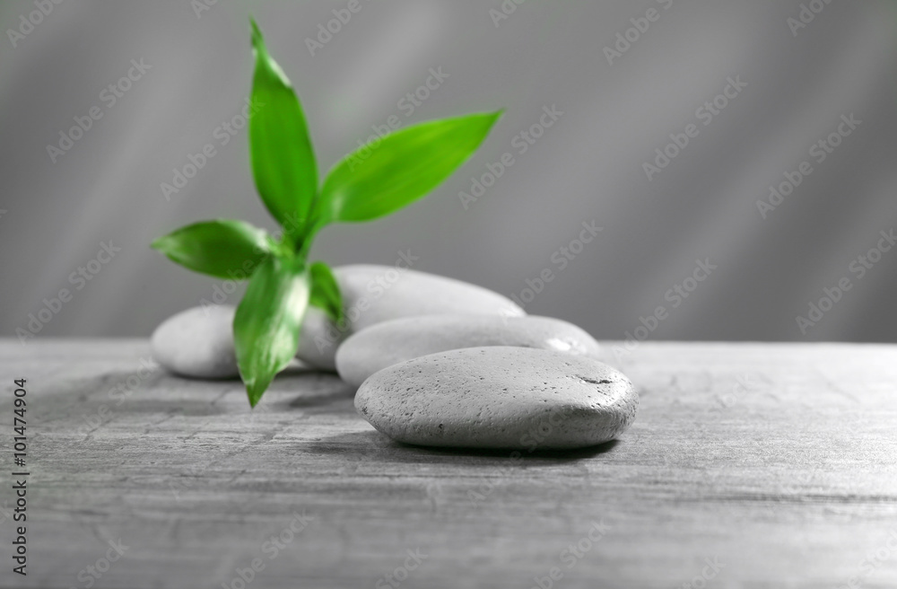 Composition of pebbles with leaf on the table against grey background Composition of pebbles with leaf on the table against grey background