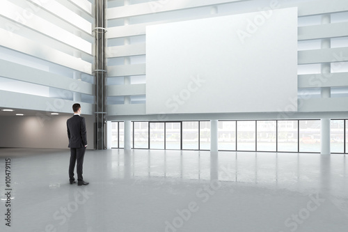 man looking at a blank white banner in a large bright hall  mock