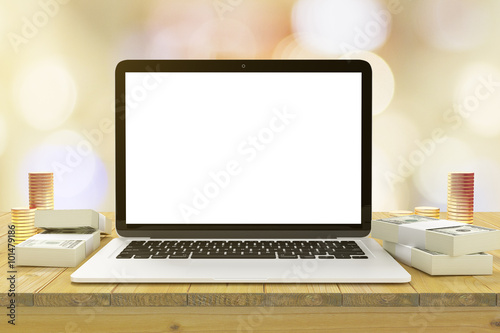 Blank laptop screen on the wooden table with bundles of money an
