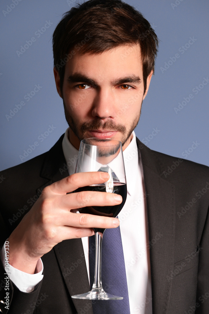 Man sniffing red wine in glass on blue background Man sniffing red wine in glass on blue background