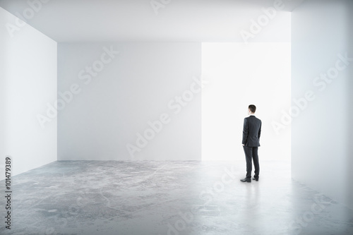 Man standing in a white room and looking to the blank wall, mock