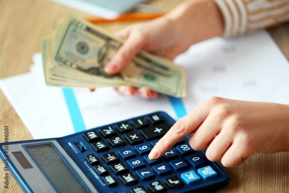 Woman counting money and working on calculator at the table Woman counting money and working on calculator at the table