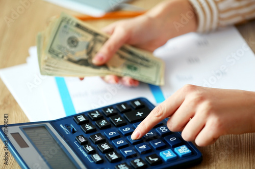 Woman counting money and working on calculator at the table