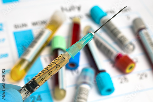hand holding syringe with serum for inyection / doctor holding syringe with blood plasma on samples in tubes