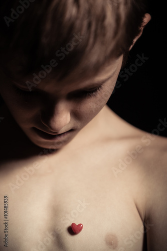 Young boy looking at a tiny red heart on his chest