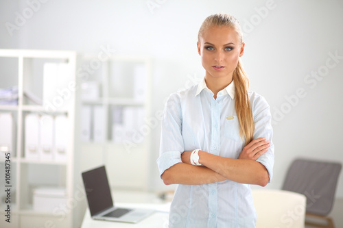 Attractive young businesswoman standing near desk in the office