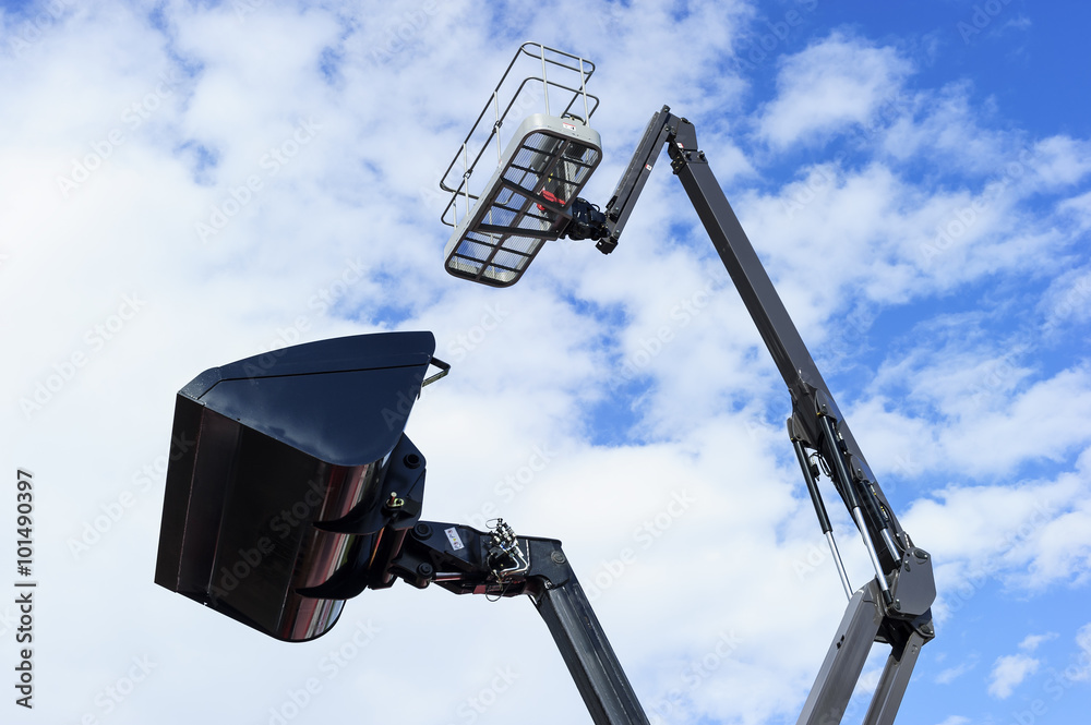 Front end loader bucket and hydraulic lift platform, construction industry, heavy machinery, blue sky and white clouds on background Front end loader bucket and hydraulic lift platform, construction industry, heavy machinery, blue sky and white clouds on background