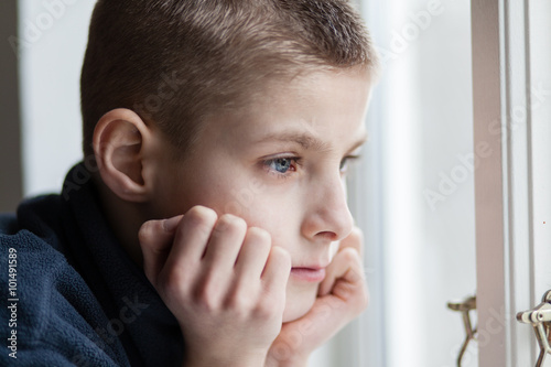 Fotografie Pensive Boy Leans his Face on Hands at the Window