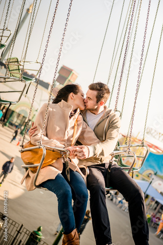 Young couple together on carousel in amusement park