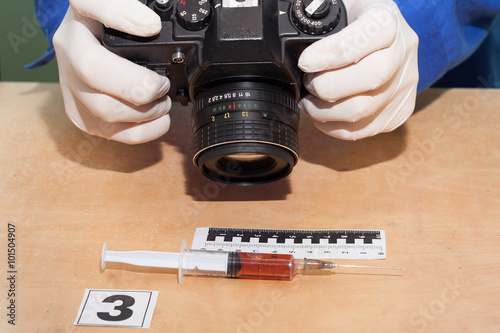 Expert photographs syringe. Crime scene. photo