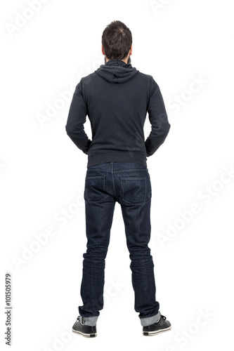 Rear view of man in black hooded shirt with rolled up jeans. Full body length portrait isolated over white studio background.