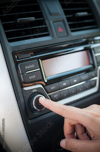 Driver finger pushing button of car audio player.