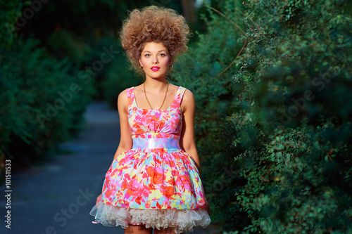 Portrait of fashion girl in pink dress and hairstyle in park. © luengo_ua