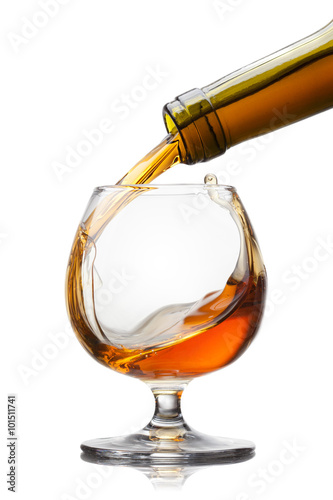 Cognac pouring into glass with splash isolated on white backgrou