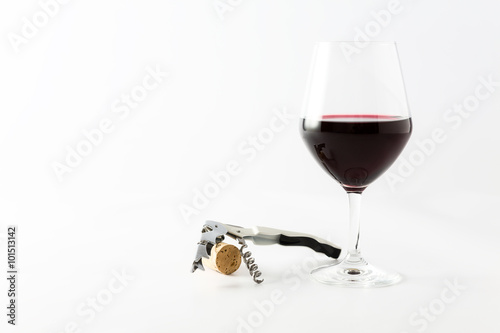 Glass of red wine with cork and corkscrew