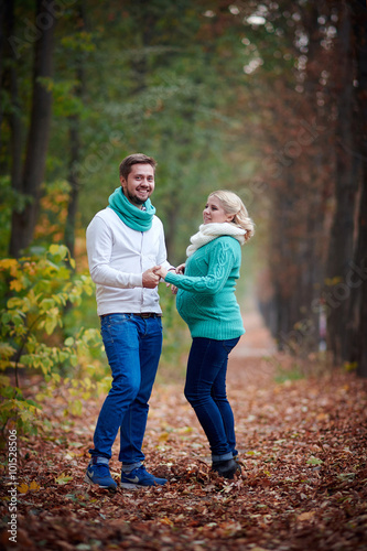 pregnant woman and a man walking in the autumn park