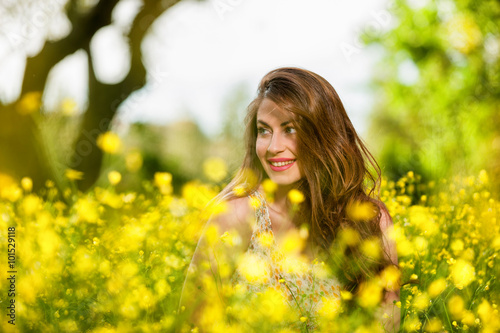 Beautiful young girl among yellow flowers