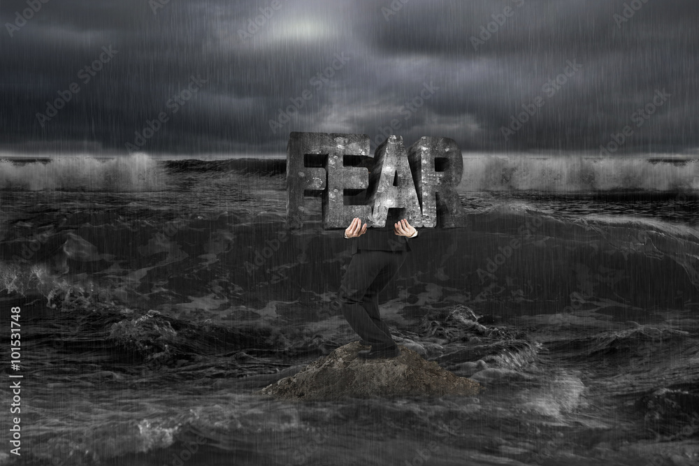 Φωτογραφία Businessman carrying old structure of FEAR on rock in dark ocean