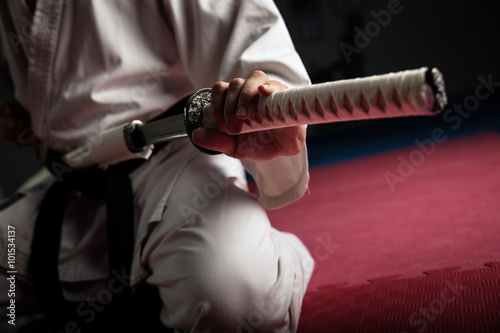 Close uo of young martial arts fighter with katana siting in seiza position