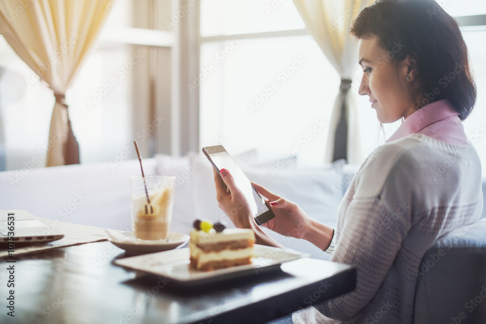 Woman in a restaurant holding digital tablet, browsing internet or connecting to wireless side view Woman in a restaurant holding digital tablet, browsing internet or connecting to wireless side view