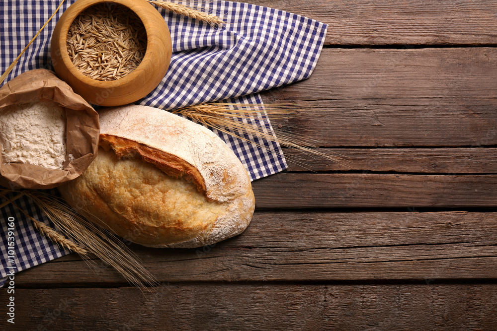 Fresh baked bread, flour, wheat and napkin on the wooden background Fresh baked bread, flour, wheat and napkin on the wooden background