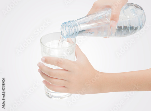 Drinking water is poured from a bottle into a glass