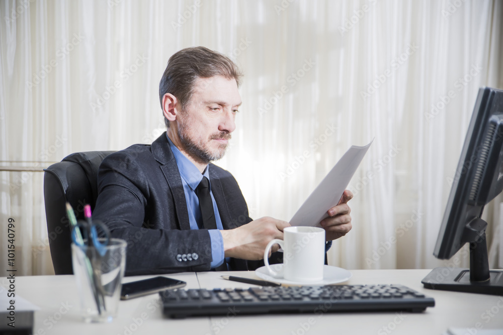 serious businessman sitting at his desk and read business documents serious businessman sitting at his desk and read business documents