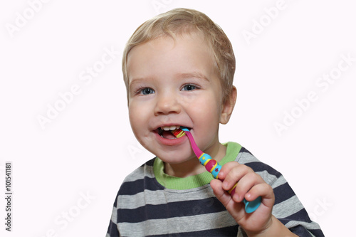 Baby with white first teeth brushing teeth with a toothbrush. Wh