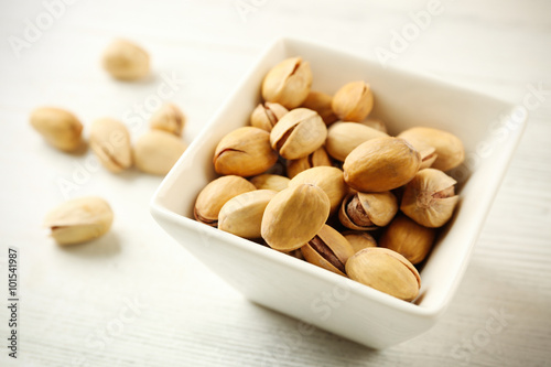 Pistachios in the bowl on white wooden background