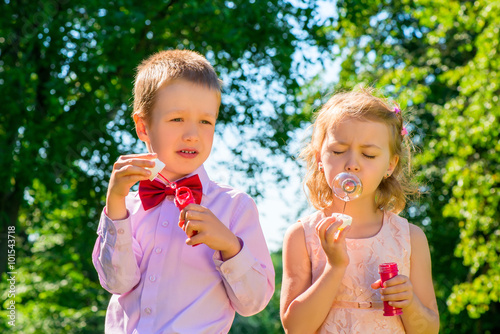 beautifully dressed kids with soap bubbles in the park