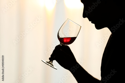 Silhouette of man sniffing red wine in a glass, close up photo