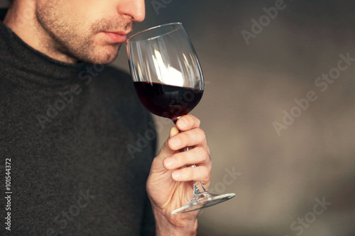 Man sniffing red wine in a glass, close up