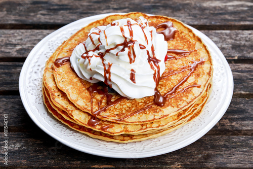 Fresh golden pancakes with cream and chocolate