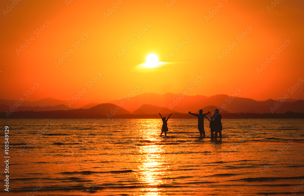 Silhouette of family on the beach at sunset.