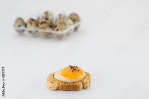 huevo frito de de codorniz sobre rebanada de pan.