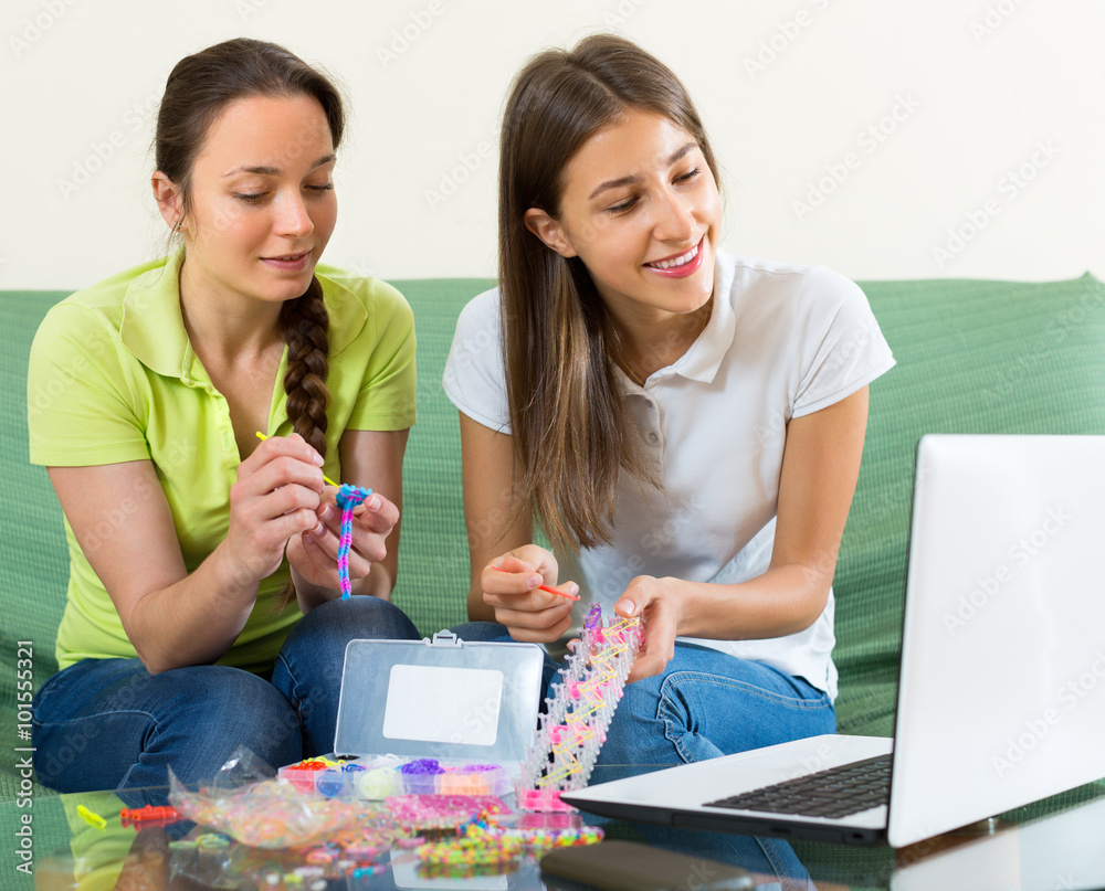 Fototapeta premium Girls braiding bracelets at home.