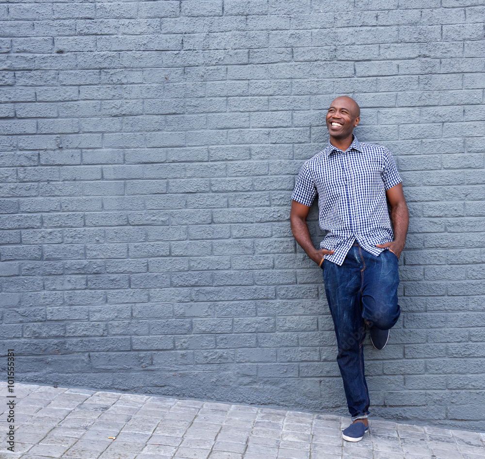 Smiling african guy leaning against gray wall Smiling african guy leaning against gray wall