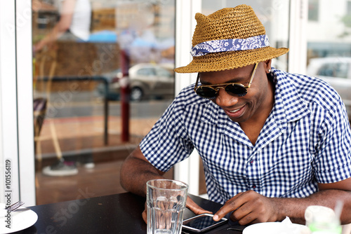 African american man sitting at outdoor cafe with cellphone
