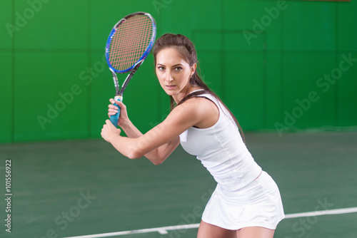 Portrait of a young woman playing tennis on court. © undrey