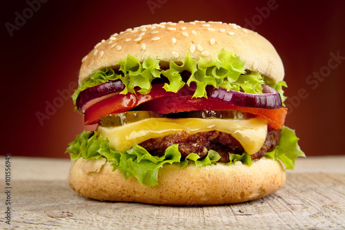 Big cheeseburger isolated on red background photo