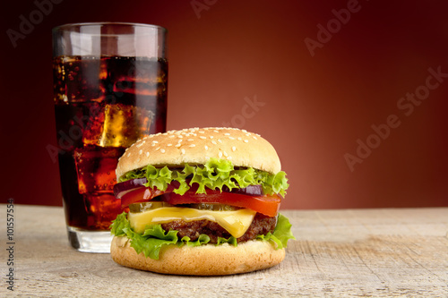 Big cheeseburger with glass of cola on red spotlight