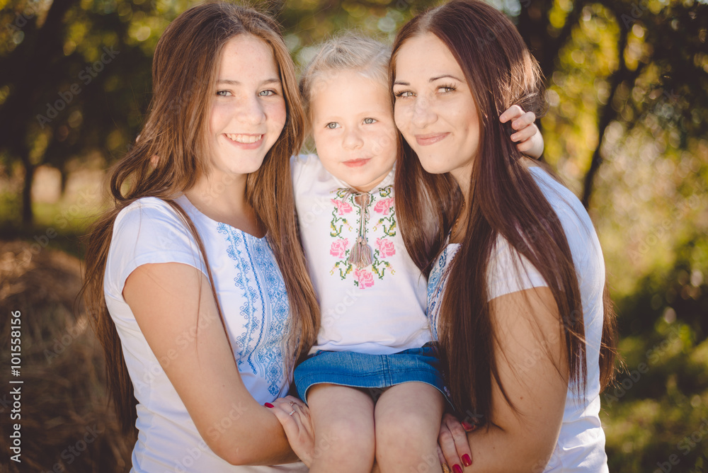 Three happy sisters hugging and smiling joyfully in summer park Three happy sisters hugging and smiling joyfully in summer park