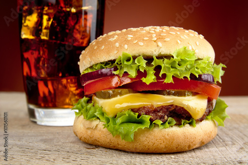 Cropped photo of cheeseburger,glass of cola on wooden table