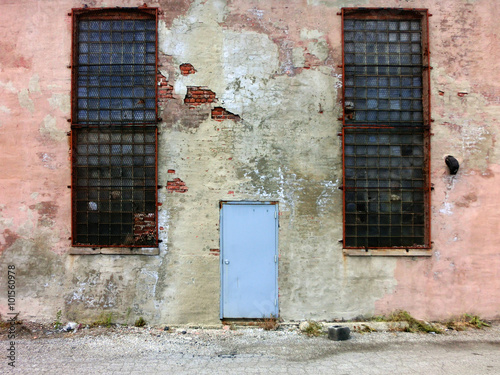 Door centered on weathered urban pink cement wall - landscape photo