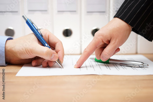 business woman is pointing where to sign on document, with docum photo