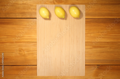 Banner for design menu of cafe or recipe cooking: three lemon lie on a bamboo panel on rustic vintage table from brown textured boards.