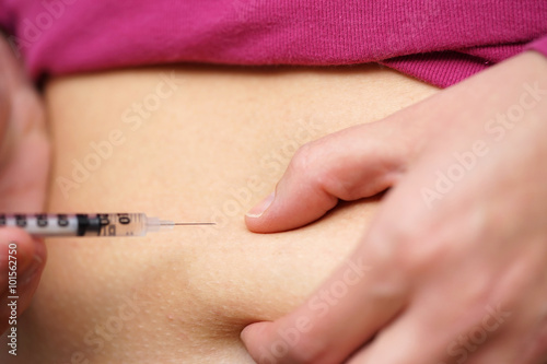 woman with diabetes give insulin shot by syringe into belly