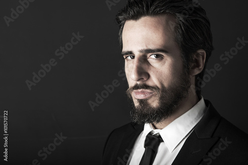 Bearded rude man with suspicius look, looking at the camera on black background